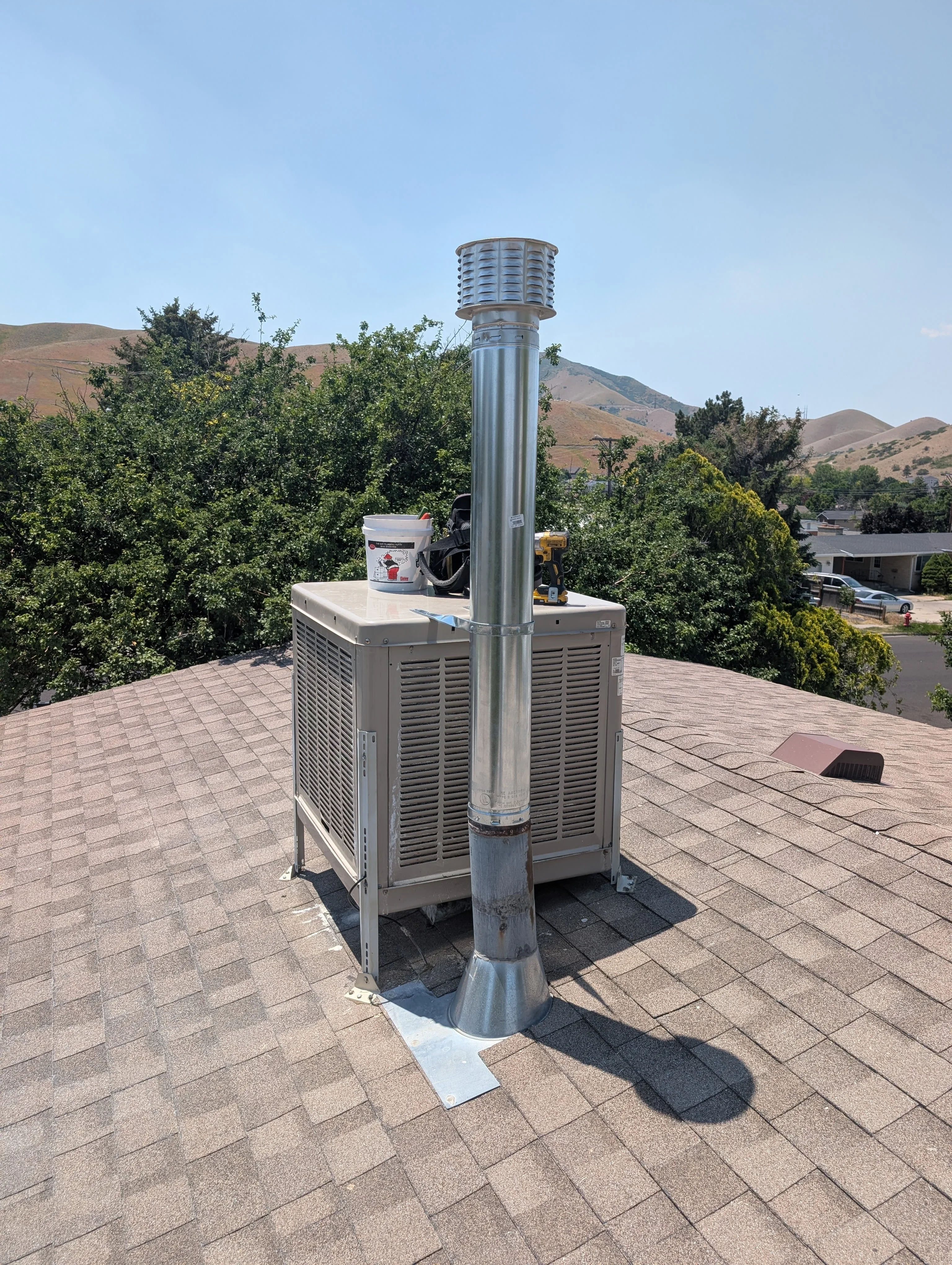 New HVAC condenser unit with metal enclosure and galvanized steel ductwork installed on residential roof