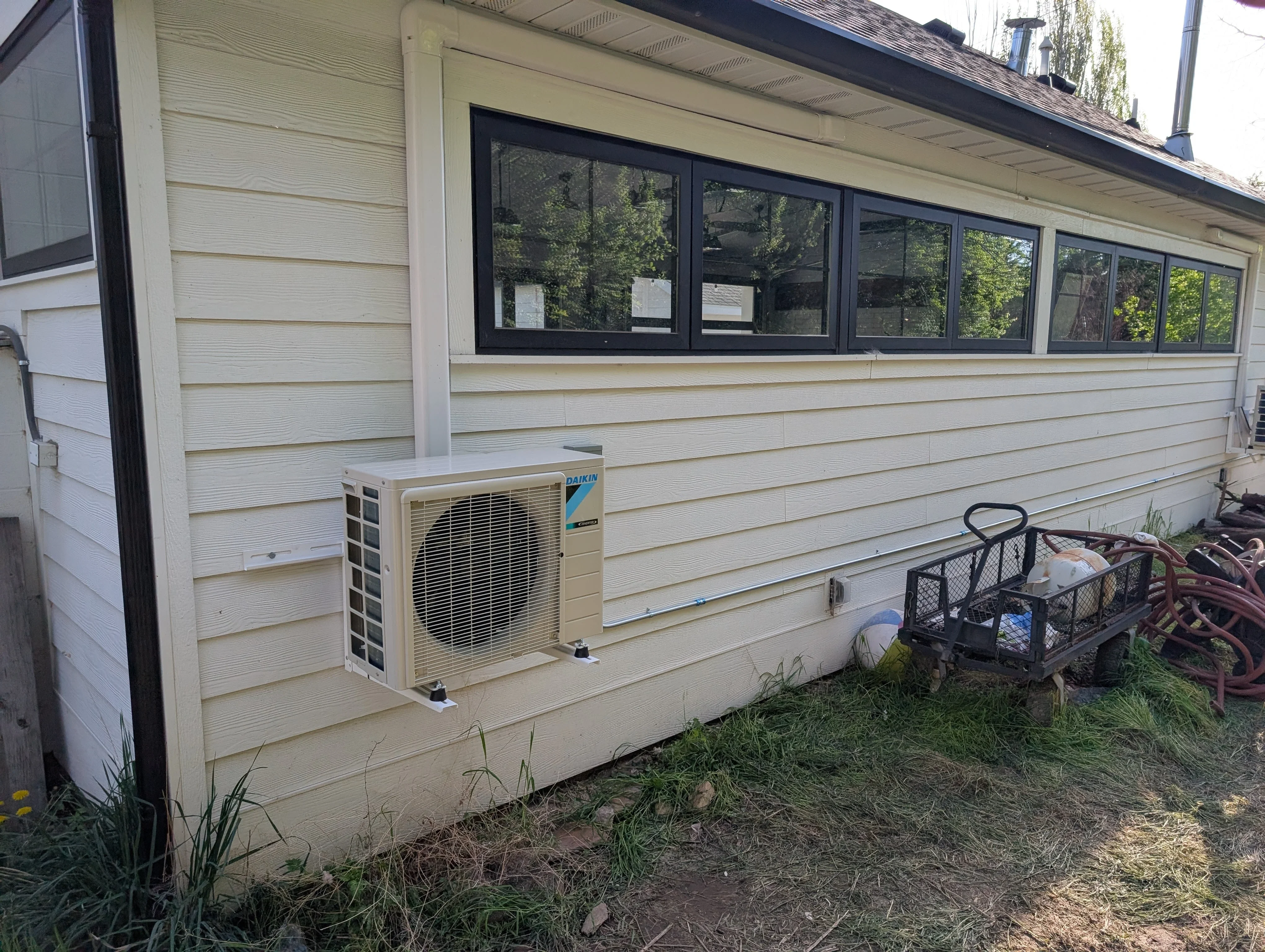 Daikin heat pump unit mounted on vinyl-sided home exterior with refrigerant lines